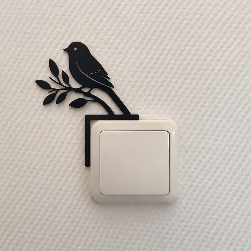 Muurdecoratie van een vogel die op een lichtschakelaar zit. Te bevestigen zonder te boren